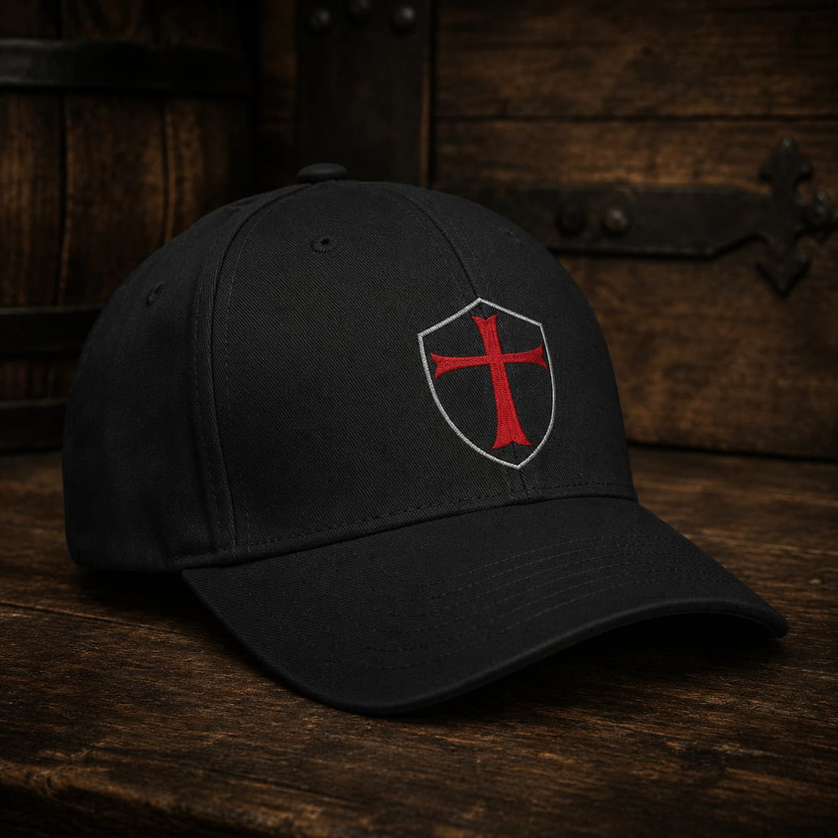 Casquette du Chevalier Templier en polyester et coton noir vue de trois quarts sur table en bois ancien sombre.