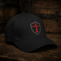 Casquette du Chevalier Templier en polyester et coton noir vue de trois quarts sur table en bois ancien sombre.