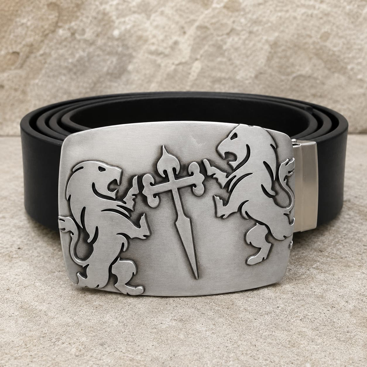 Ceinture Cœur de Lion en cuir noir avec boucle argentée en alliage de zinc ornée de deux lions et d’une épée sur fond pierre claire.