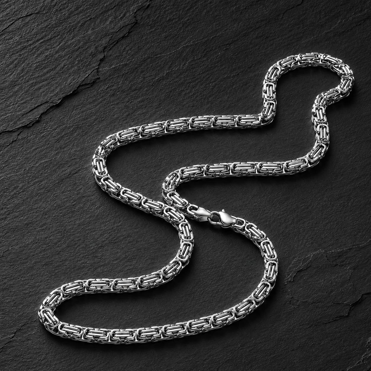 Chaîne du Temple en acier inoxydable premium argentée sur fond anthracite texturé.
