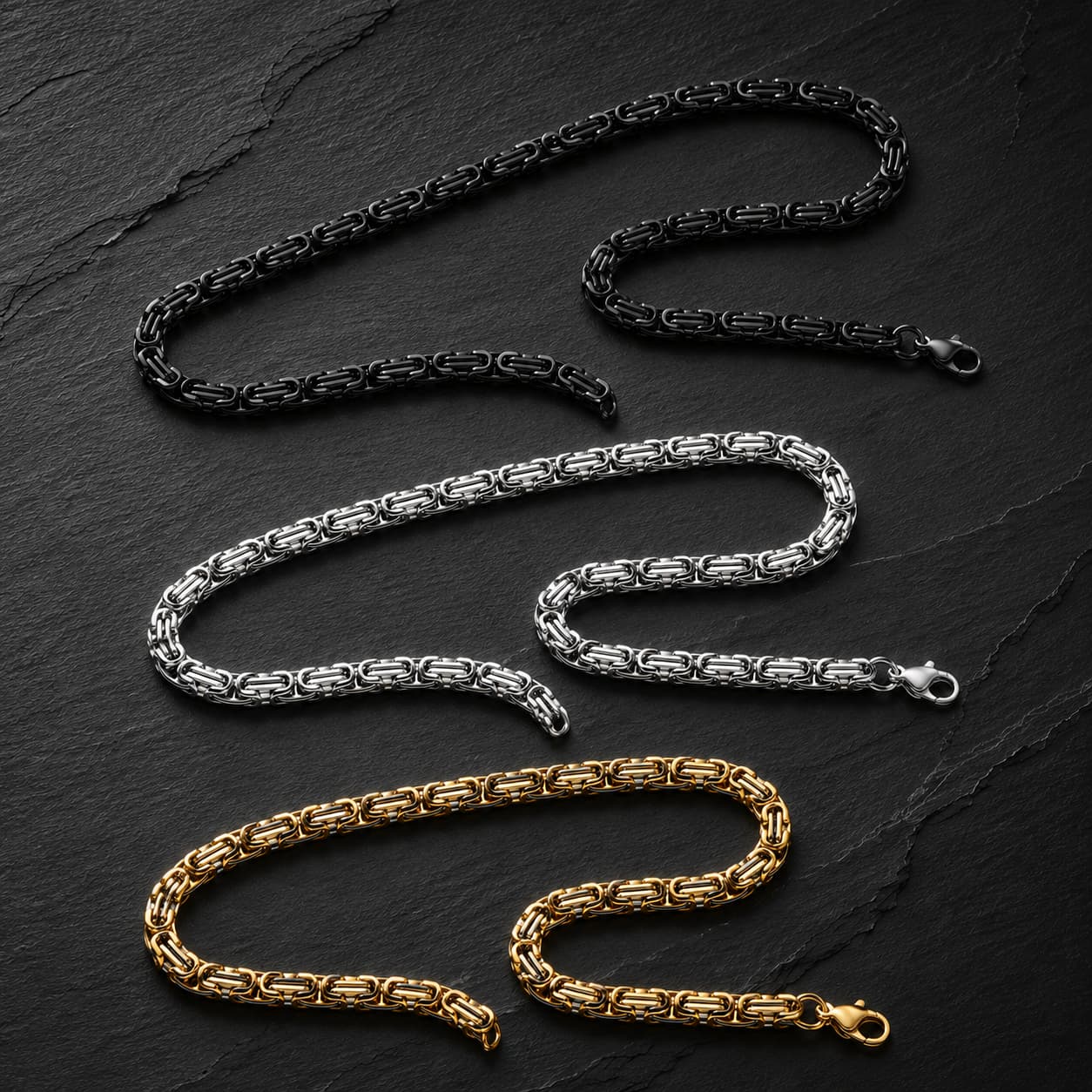Variantes noir, argent et doré de la Chaîne du Temple en acier inoxydable premium présentées sur fond sombre.