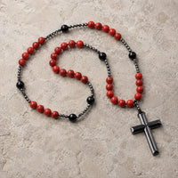 Chapelet de la Sacristie en alliage métallique et pierres synthétiques avec perles rouges et noires sur pierre médiévale claire.