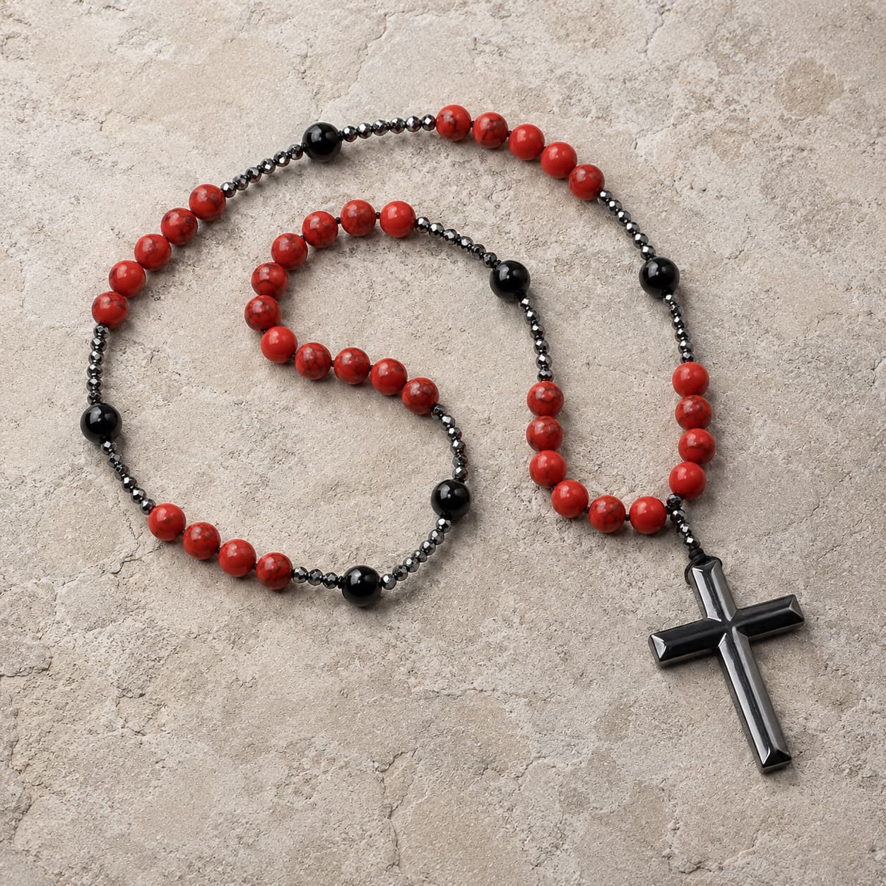 Chapelet de la Sacristie en alliage métallique et pierres synthétiques avec perles rouges et noires sur pierre médiévale claire.