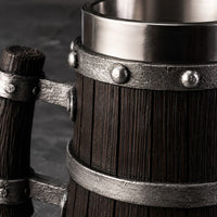 Gros plan sur la texture bois sombre et les cerclages en métal riveté de la Chope de Bière du Temple.