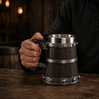 Homme tenant la Chope de Bière du Temple en résine avec intérieur en acier inoxydable dans une taverne sombre.