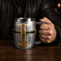 Homme tenant la Chope du Heaume Templier en résine avec intérieur en acier inoxydable dans un décor sombre de taverne médiévale.