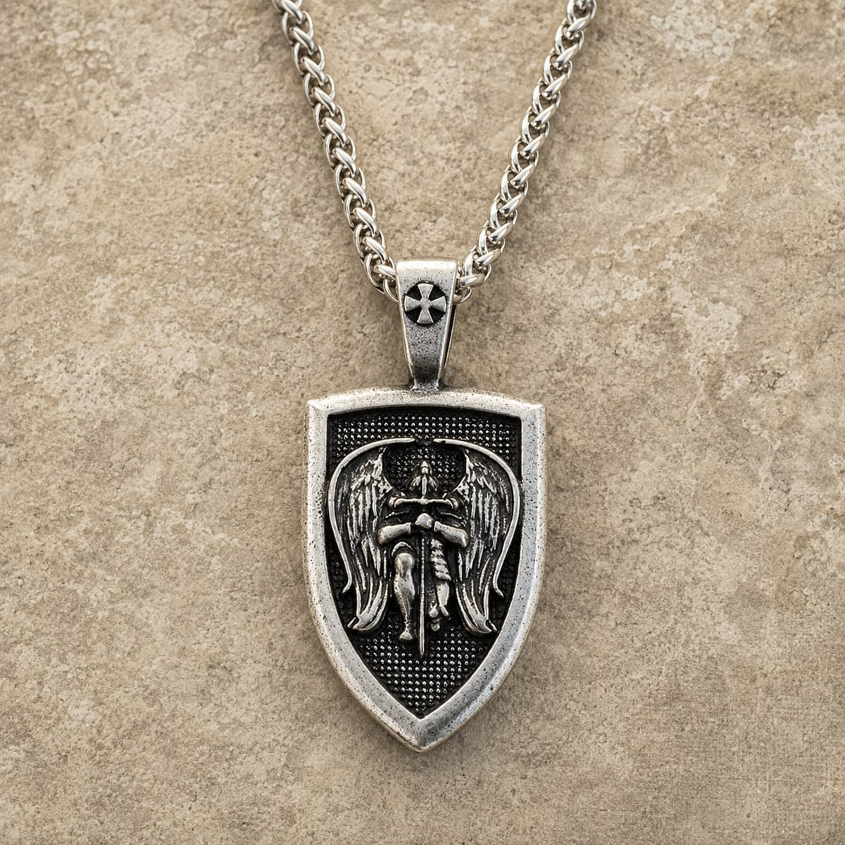 Collier de l’Archange Michel en acier inoxydable avec pendentif bouclier sur fond pierre médiévale claire
