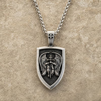 Collier de l’Archange Michel en acier inoxydable avec pendentif bouclier sur fond pierre médiévale claire