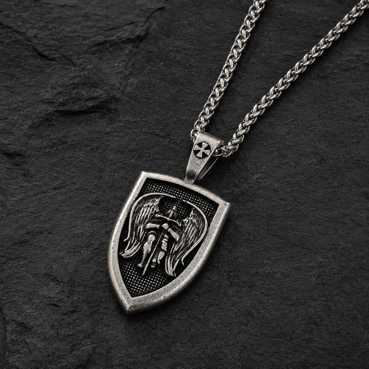 Vue angle du Collier de l’Archange Michel en acier inoxydable sur fond ardoise sombre texturée