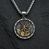 Collier Bouclier de Saint Michel en acier inoxydable avec médaille argentée et dorée sur fond anthracite texturé.