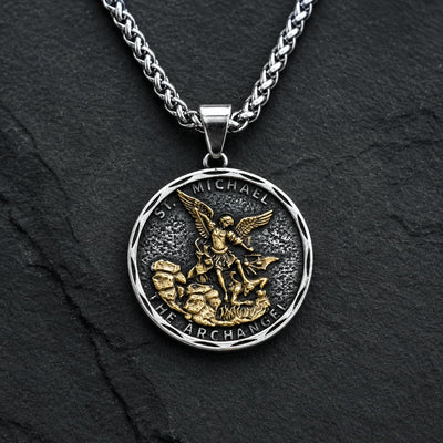 Collier Bouclier de Saint Michel en acier inoxydable avec médaille argentée et dorée sur fond anthracite texturé.