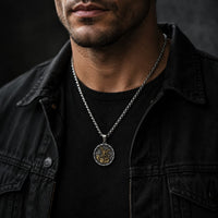 Collier Bouclier de Saint Michel en acier inoxydable porté par un homme en tenue noire dans une ambiance sombre.