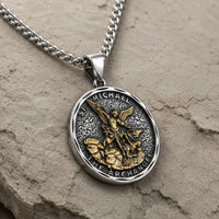 Vue angle 3/4 du Collier Bouclier de Saint Michel en acier inoxydable sur fond pierre médiévale claire beige-gris.