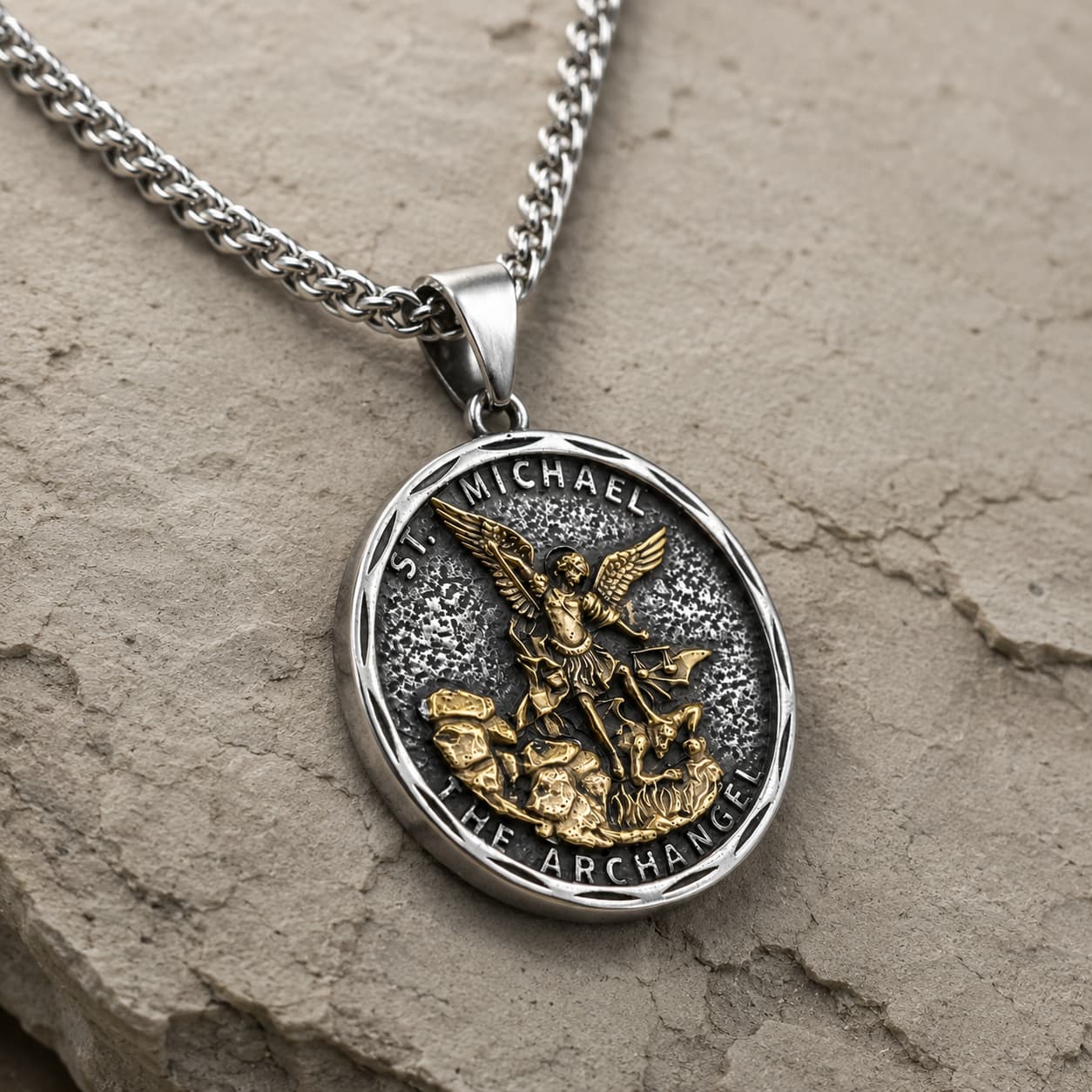 Vue angle 3/4 du Collier Bouclier de Saint Michel en acier inoxydable sur fond pierre médiévale claire beige-gris.