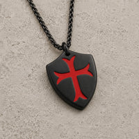 Collier de la Chevalerie version noire avec pendentif bouclier templier et croix rouge sur fond pierre médiévale