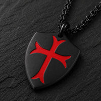 Gros plan du Collier de la Chevalerie noir avec bouclier templier et croix rouge sur ardoise sombre
