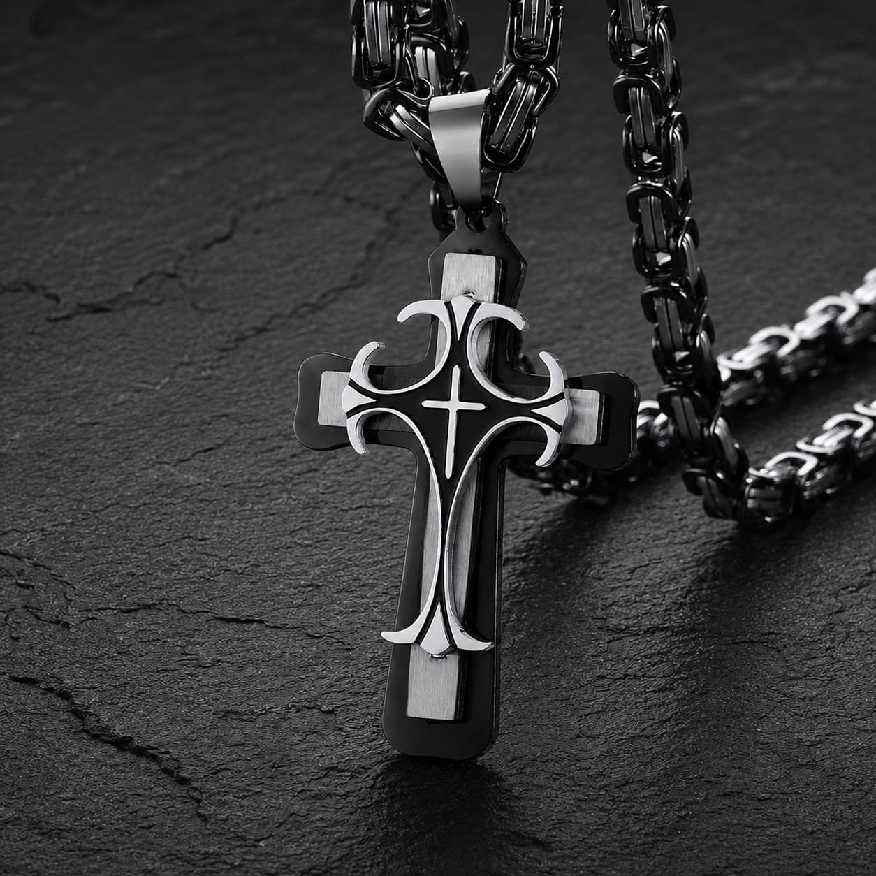 Collier Croisé de l’Espoir en acier inoxydable noir et argenté avec pendentif croix sur fond ardoise sombre