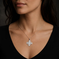 Collier Croix de l'Ordre de Jérusalem en acier inoxydable premium porté par une femme sobre en tenue noire à col dégagé.