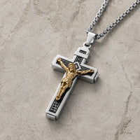 Vue 3/4 du Collier Croix de la Passion en acier inoxydable argenté avec Christ doré sur fond pierre médiévale claire.