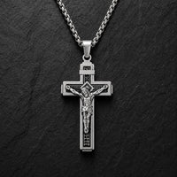 Variante argentée du Collier Croix de la Passion en acier inoxydable sur fond anthracite texturé.