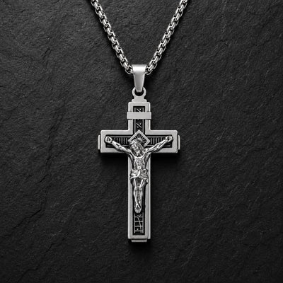 Variante argentée du Collier Croix de la Passion en acier inoxydable sur fond anthracite texturé.