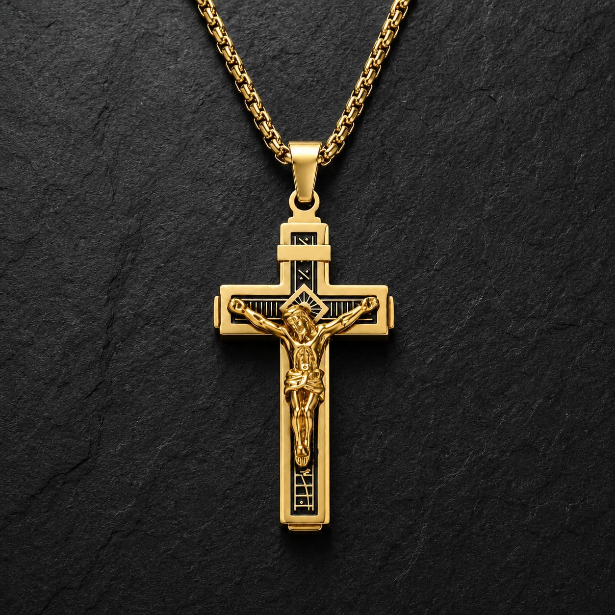 Variante dorée du Collier Croix de la Passion en acier inoxydable sur fond anthracite texturé.