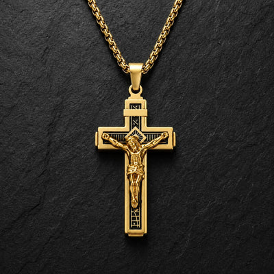 Variante dorée du Collier Croix de la Passion en acier inoxydable sur fond anthracite texturé.