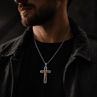Homme portant le Collier Croix de la Passion en acier inoxydable argenté avec Christ doré, tenue noire et ambiance sombre.