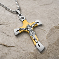 Collier de l’Ascension du Croisé en acier inoxydable doré et argenté avec pendentif crucifix en vue angle 3/4 sur pierre médiévale claire