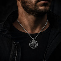 Homme portant le Collier de l’Espoir du Christ en acier inoxydable avec tenue noire et veste sombre.