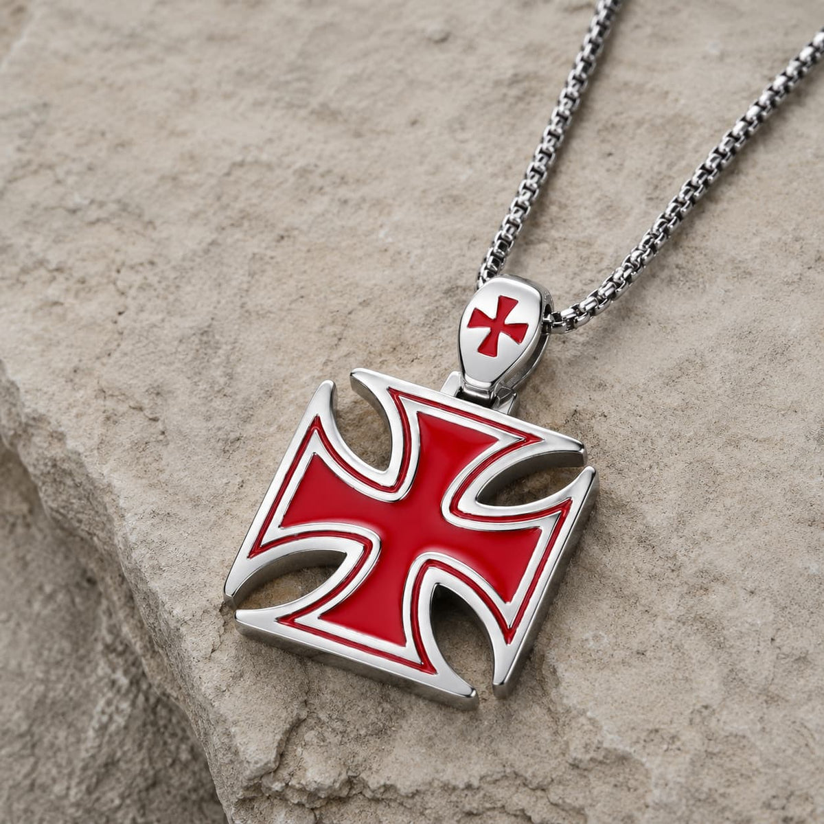 Collier de la Bravoure Templière en acier inoxydable avec pendentif croix rouge posé sur pierre médiévale claire