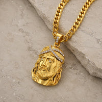 Collier de la Foi du Christ en acier inoxydable doré vue angle 3 4 sur pierre médiévale claire beige gris