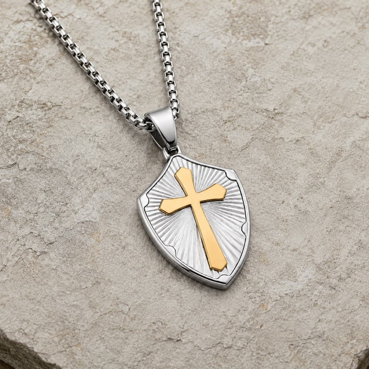 Collier de la Sagesse Templière en acier inoxydable argenté avec croix dorée en vue angle 3/4 sur pierre médiévale claire