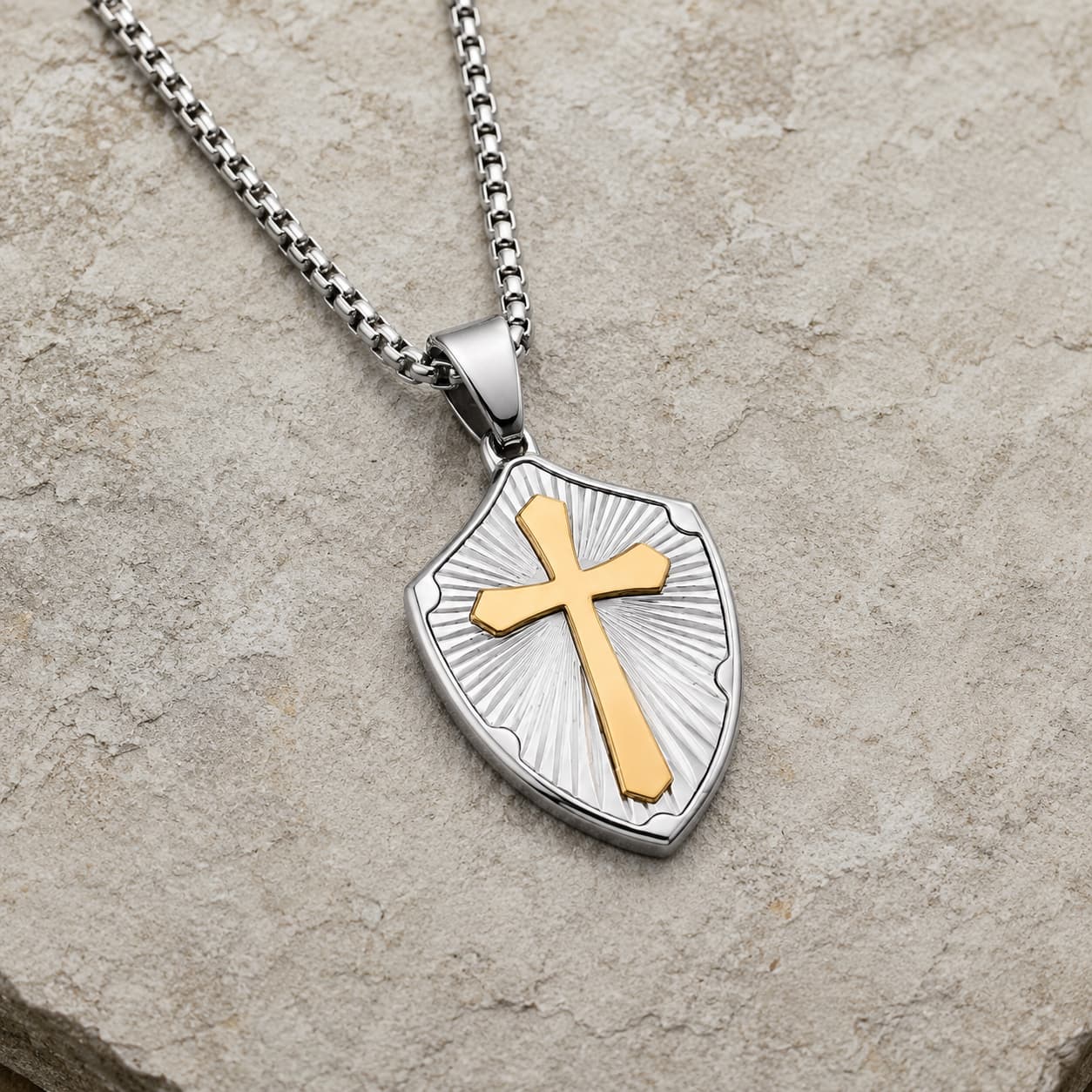 Collier de la Sagesse Templière en acier inoxydable argenté avec croix dorée en vue angle 3/4 sur pierre médiévale claire
