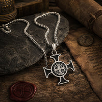 Collier de Saint Benoit en acier inoxydable présenté dans une ambiance médiévale avec bois ancien, parchemin et lumière chaude