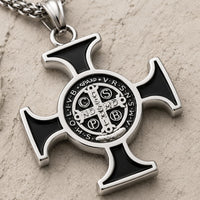 Gros plan de la médaille centrale du Collier de Saint Benoit en acier inoxydable sur pierre médiévale claire