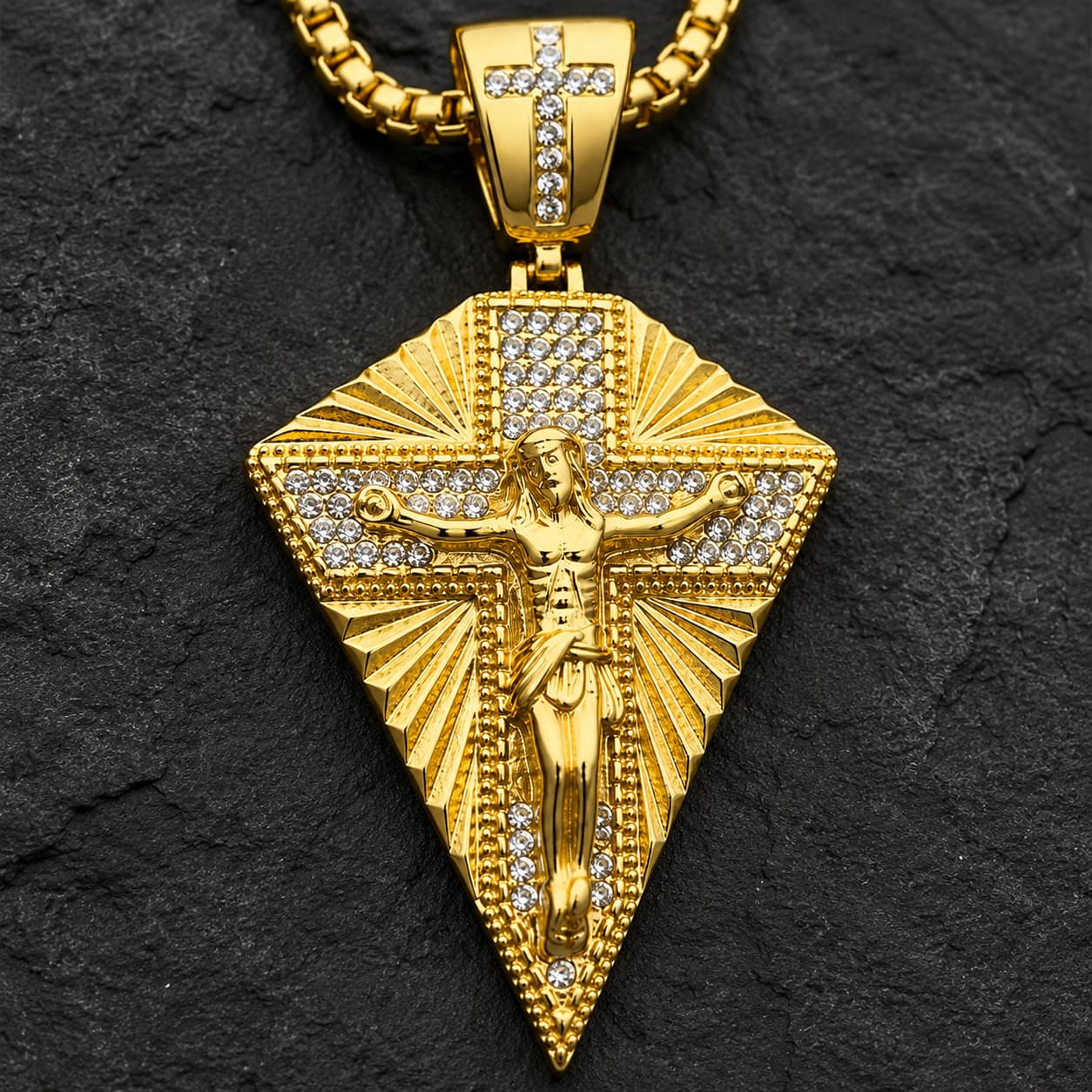 Collier du Christ Sacré en acier inoxydable doré avec zircon cubique sur fond anthracite texturé.