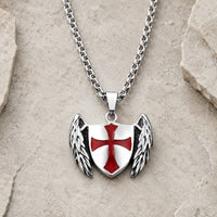 Collier du Gardien Croisé en acier inoxydable avec pendentif bouclier ailé et croix rouge sur fond pierre médiévale claire