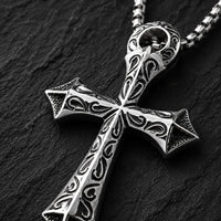 Gros plan du pendentif croix du Collier du Justicier Croisé en acier inoxydable sur fond anthracite texturé.