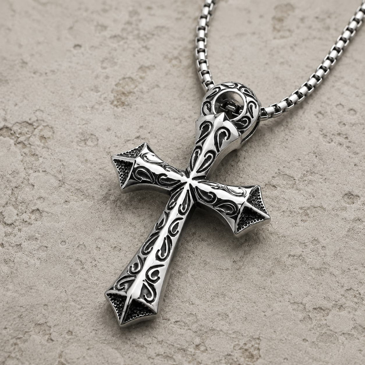 Vue angle 3/4 du Collier du Justicier Croisé en acier inoxydable sur fond pierre médiévale claire beige-gris.