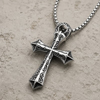 Vue angle 3/4 du Collier du Justicier Croisé en acier inoxydable sur fond pierre médiévale claire beige-gris.