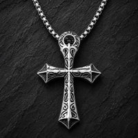 Collier du Justicier Croisé en acier inoxydable avec pendentif croix argenté sur fond anthracite texturé ardoise sombre.