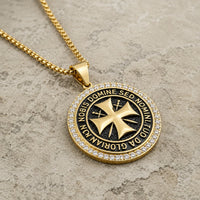 Collier du Maître Templier en acier inoxydable doré avec pendentif croix templière en vue angle 3/4 sur pierre médiévale claire