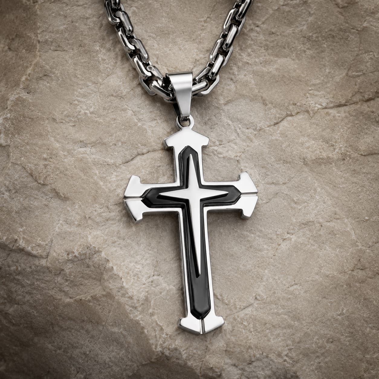 Collier du Gardien du Temple en acier inoxydable noir et argenté sur fond pierre médiévale claire.