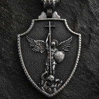 Gros plan du pendentif Saint Michel du Collier Honneur de Saint Michel en acier inoxydable sur fond anthracite