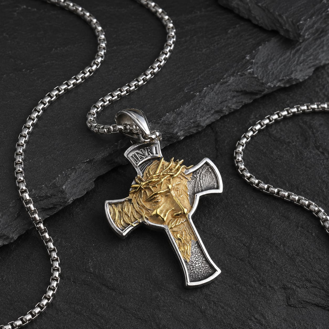 Détail du Collier Inri Sacré en acier inoxydable argenté et doré sur fond anthracite sombre