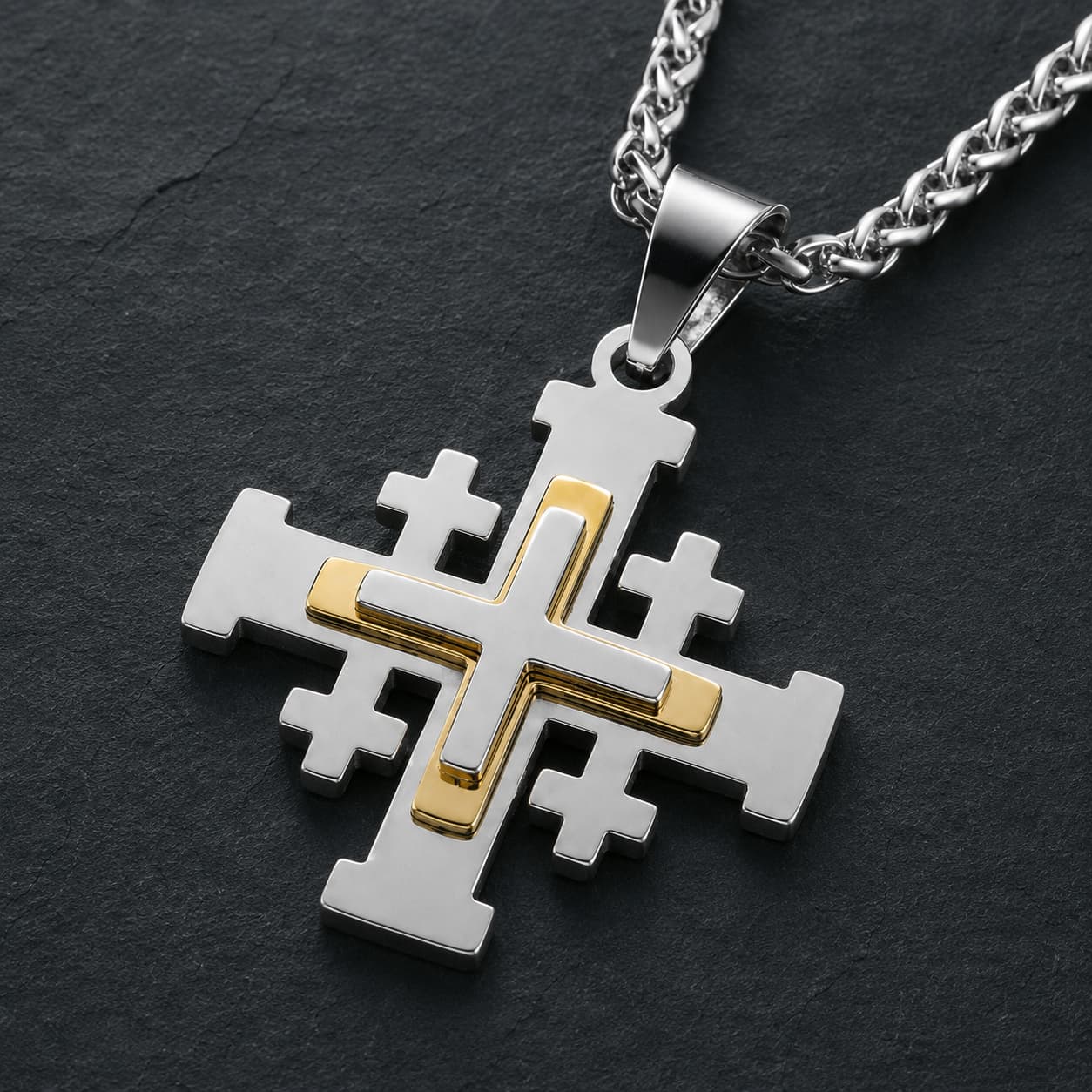 Gros plan de la croix argentée et dorée du Collier de l’Ordre du Saint Sépulcre en acier inoxydable sur fond anthracite