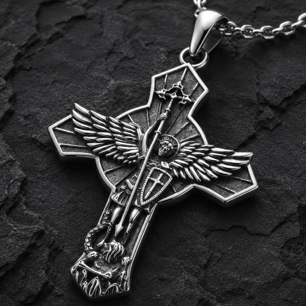 Gros plan du motif du Collier Protection de Saint Michel en argent 925 sterling sur fond anthracite texturé