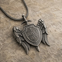 Vue angle 3/4 du Collier Quis Ut Deus en acier inoxydable sur fond pierre médiévale claire.