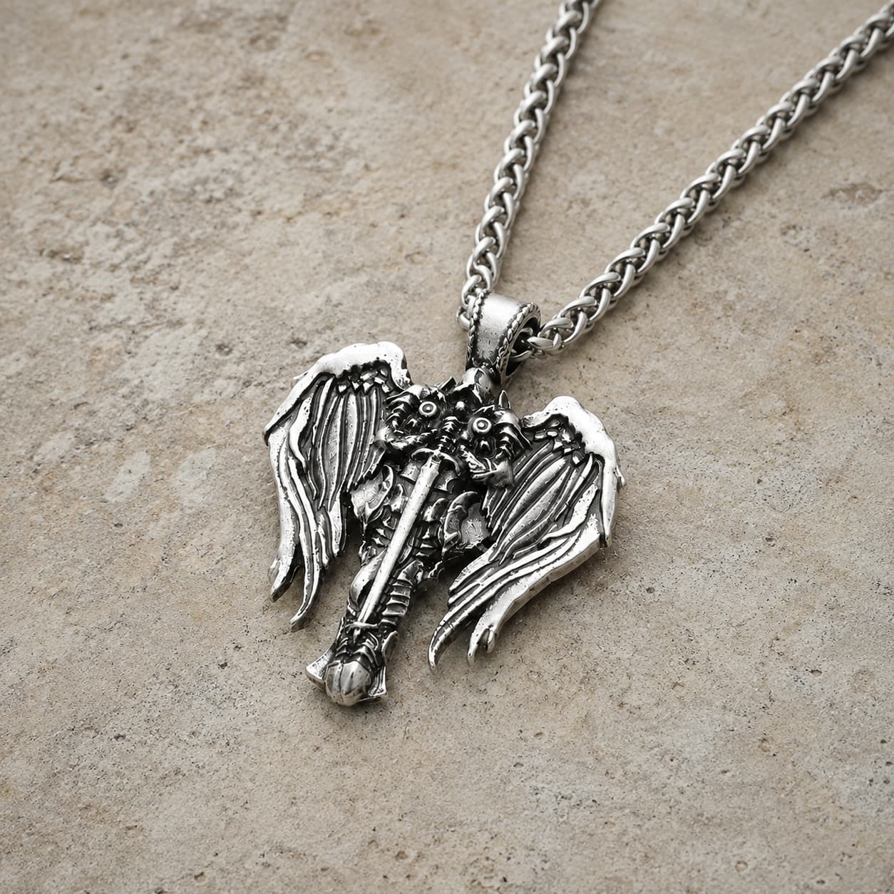 Vue angle du Collier Sacré de l'Archange en acier inoxydable sur pierre médiévale claire